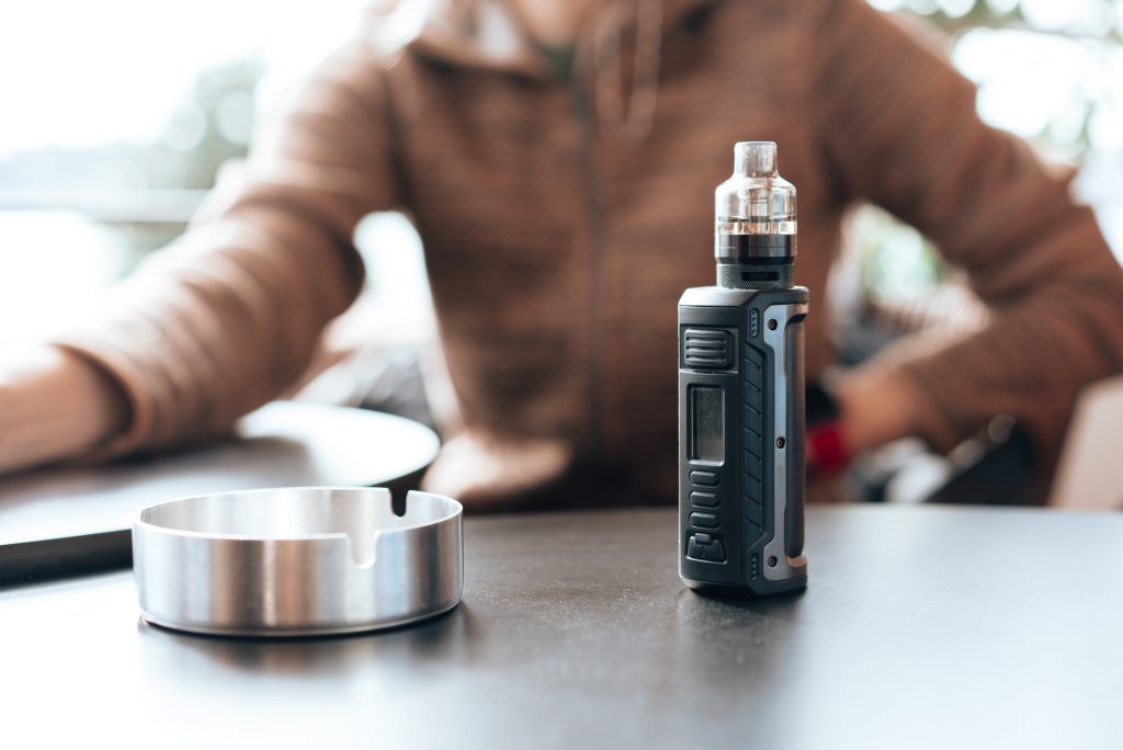 Vape stands on a wooden table in cafe close up